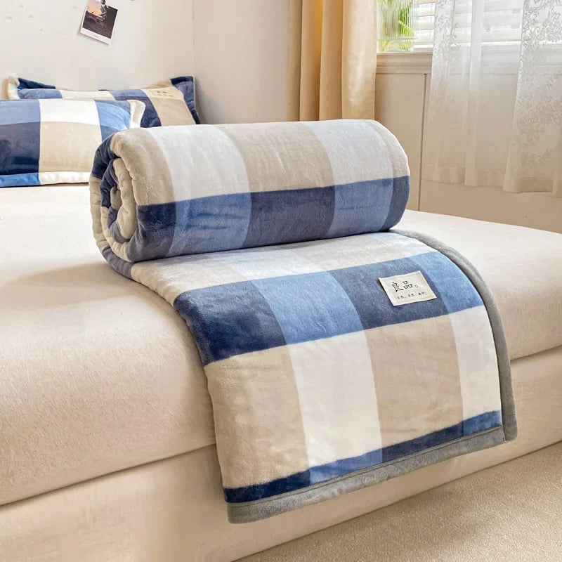 Une couverture douce et confortable dans des tons bleus et beiges, posée sur un canapé, évoquant le confort et la relaxation.
