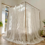 Lit à baldaquin en bois avec de magnifiques rideaux en dentelle blanche, créant une ambiance romantique et chaleureuse dans la chambre.