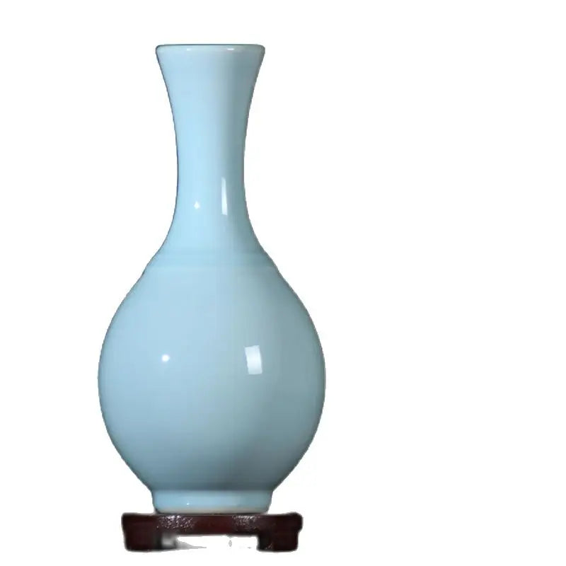 Un vase bleu clair en céramique élégant posé sur un socle en bois foncé.