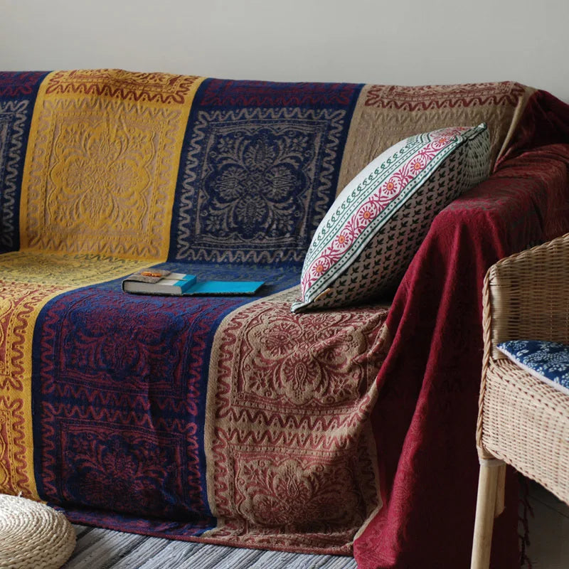 Des coussins décoratifs aux motifs floraux et ethniques ornent un canapé rustique, créant une ambiance chaleureuse et accueillante dans cette pièce.