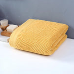 Une magnifique couverture en maille jaune, délicatement texturée avec un motif géométrique subtil, apportant une touche de chaleur et de style à n'importe quel espace.