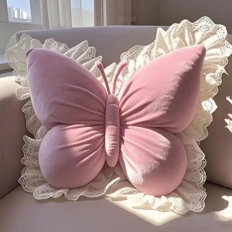 Coussin décoratif en forme de papillon rose avec dentelle, sur un canapé lumineux.