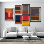 Ensemble de toiles abstraites aux couleurs vives accrochées sur un mur blanc dans un salon moderne avec un canapé blanc et une table basse en marbre.