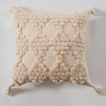 Coussin décoratif beige moelleux avec motif de pompons texturés.