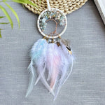 Une belle attrape-rêves artisanale suspendue sur un fond vert, avec des plumes douces et délicates qui s'entrelacent dans un design élégant et apaisant.