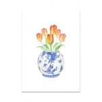 Un bouquet de tulipes orange et jaunes dans un vase en porcelaine bleue et blanche aux motifs floraux.