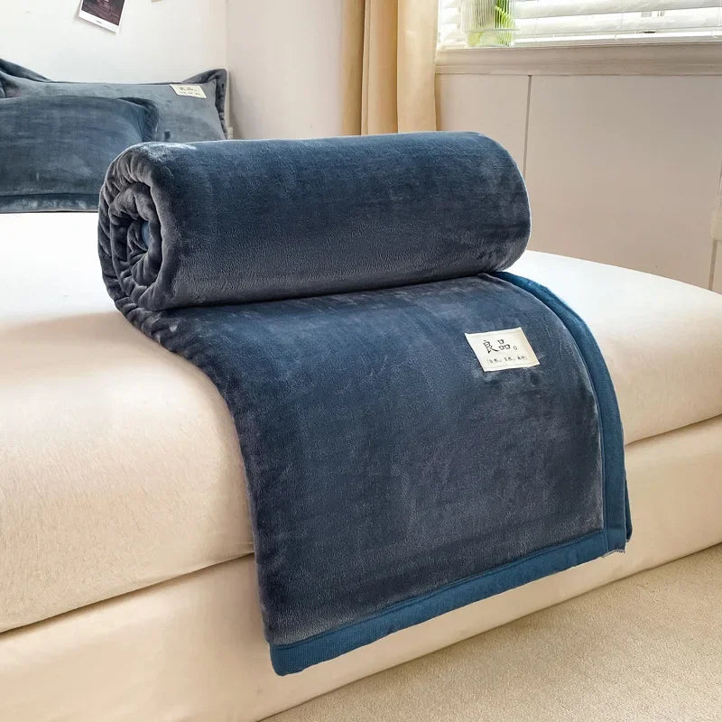 Une couverture en polaire gris foncé, douillette et moelleuse, posée sur un canapé clair dans un intérieur chaleureux.