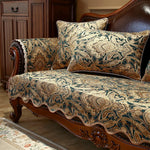 Un canapé en bois sombre décoré de coussins aux motifs floraux et géométriques, créant une ambiance chaleureuse et élégante dans cette pièce de style classique.