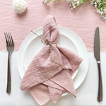 Une magnifique table avec une nappe rose pastel, des fleurs fraîches et des couverts en argent, créant une atmosphère élégante et raffinée.