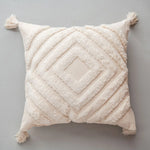 Coussin moelleux beige avec motif géométrique décoratif en relief, créant une texture douce et chaleureuse.