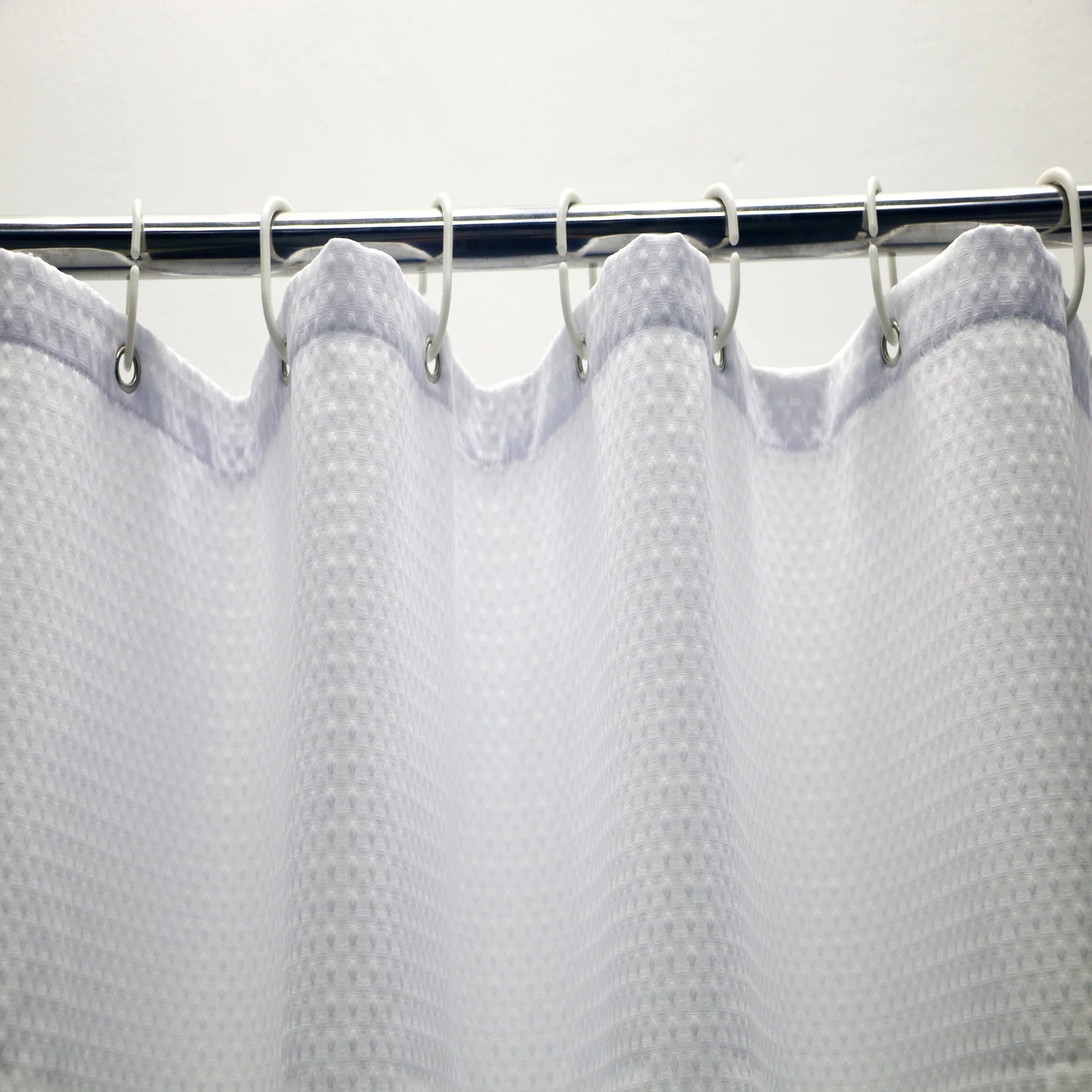 Rideau de douche en maille blanche, ajoutant une touche moderne et élégante à une salle de bain équipée de fixtures de plomberie. Idéal pour compléter n'importe quel décor de salle de bain avec son design unique.