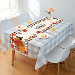 Une table d'automne avec une nappe à carreaux, des feuilles rouges, une belle fleur rose et une décoration de citrouille, créant une ambiance chaleureuse et accueillante pour une célébration automnale.