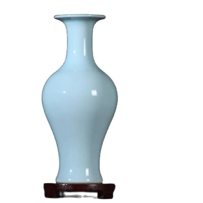 Un vase bleu céladon élégant et raffiné sur un support en bois foncé.