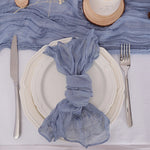 Un arrangement de table élégant avec une assiette blanche, des couverts en acier inoxydable et un drapé bleu clair décoratif.