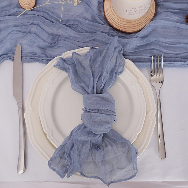 Un arrangement de table élégant avec une assiette blanche, des couverts en acier inoxydable et un drapé bleu clair décoratif.