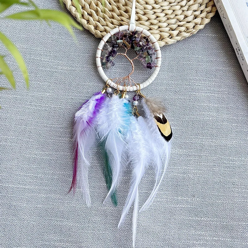Un attrapeur de rêves décoratif avec un cercle en métal, des plumes multicolores et des pierres d'améthyste disposées avec soin.
