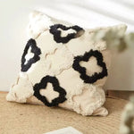 Coussin décoratif en peluche blanche avec des motifs de cœurs noirs donnant un aspect soyeux et moelleux.