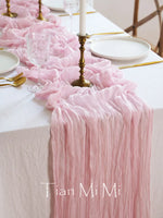Une table élégante drapée de tissu rose plissé, ornée de bougies allumées, de verres cristallins et d'une assiette blanche, créant une atmosphère sophistiquée et romantique.