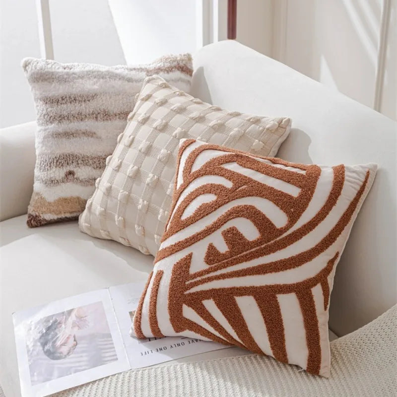 Coussin décoratif en jacquard avec motif géométrique abstrait sur un canapé blanc dans un intérieur lumineux.