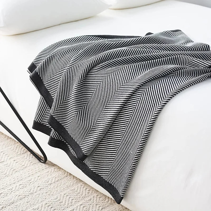 Cette image montre une couverture noire et blanche avec un motif de lignes diagonales répétées, créant un effet visuel intéressant et élégant.