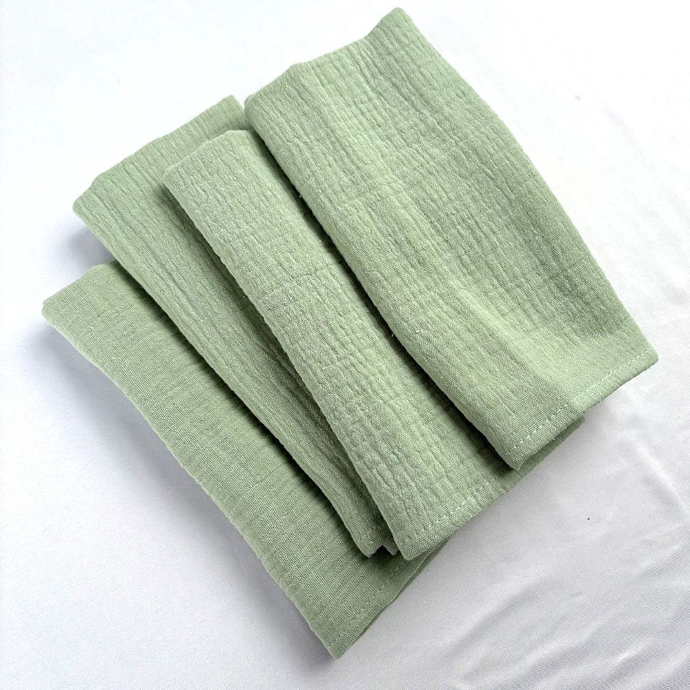 Des serviettes de douche de couleur vert pâle posées sur une surface blanche.