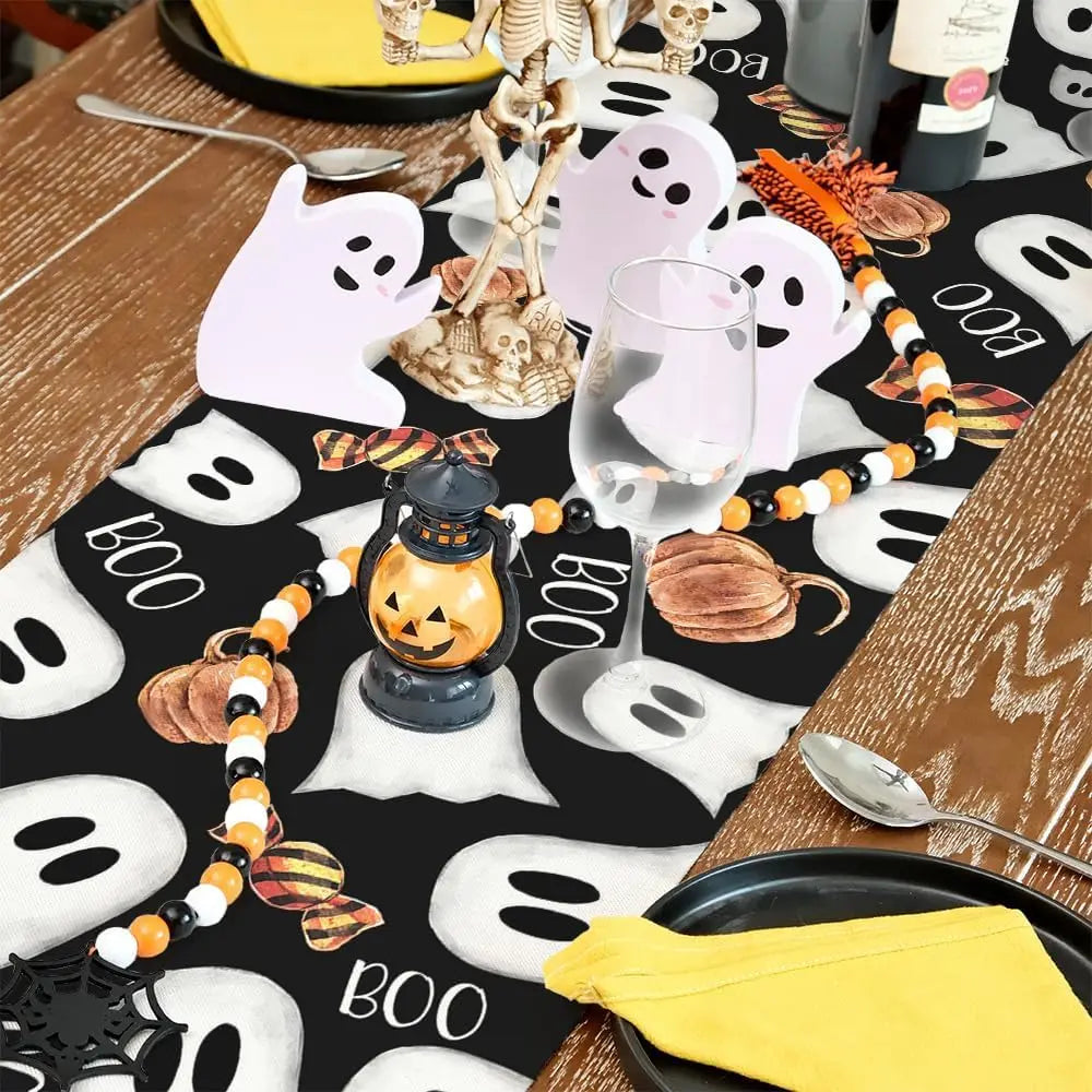 Décoration de table d'Halloween avec fantômes blancs, citrouille, guirlande et bougies sur un fond sombre.