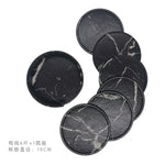 Des dessous-de-plat ronds en pierre noire avec des veines blanches, idéaux pour protéger les surfaces des tables.