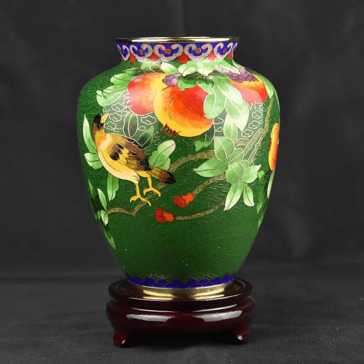 Un magnifique vase en céramique décoré de motifs floraux et d'un oiseau, sur un fond vert profond.