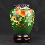 Un magnifique vase en céramique décoré de motifs floraux et d'un oiseau, sur un fond vert profond.