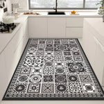 Tapis noir et blanc avec des motifs décoratifs géométriques et floraux dans un style vintage, placé dans une cuisine moderne avec des meubles blancs.
