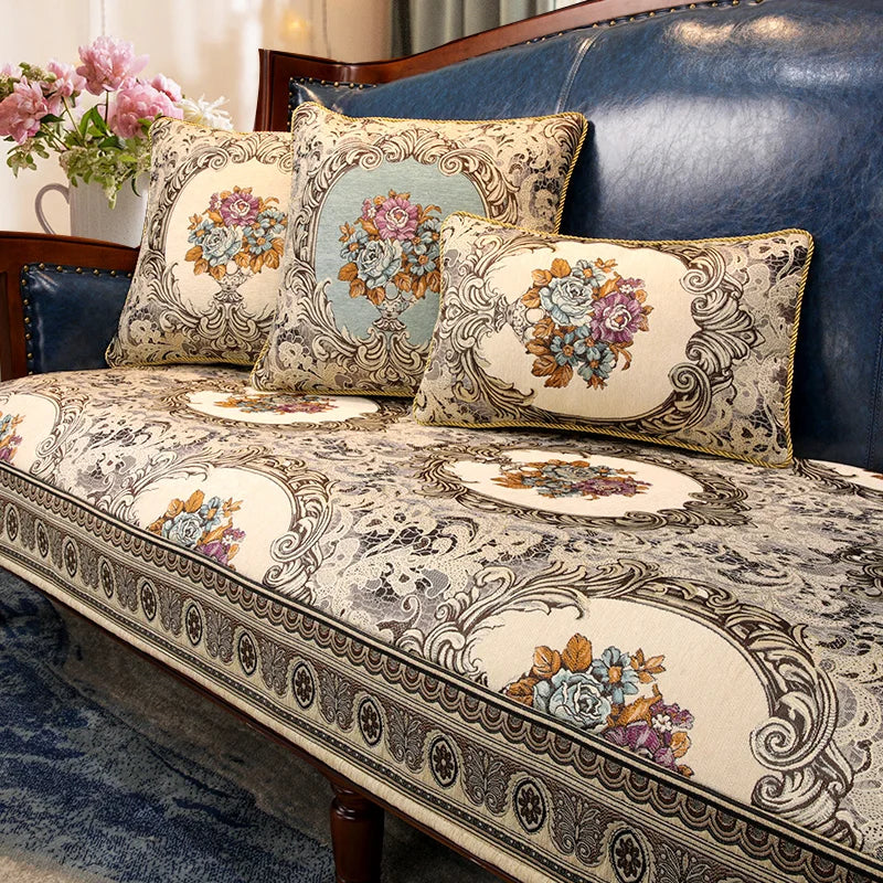 Un canapé en bois avec des coussins décorés de motifs floraux et de bordures ornementées, dans des tons de beige et de bleu, créant une atmosphère élégante et raffinée.