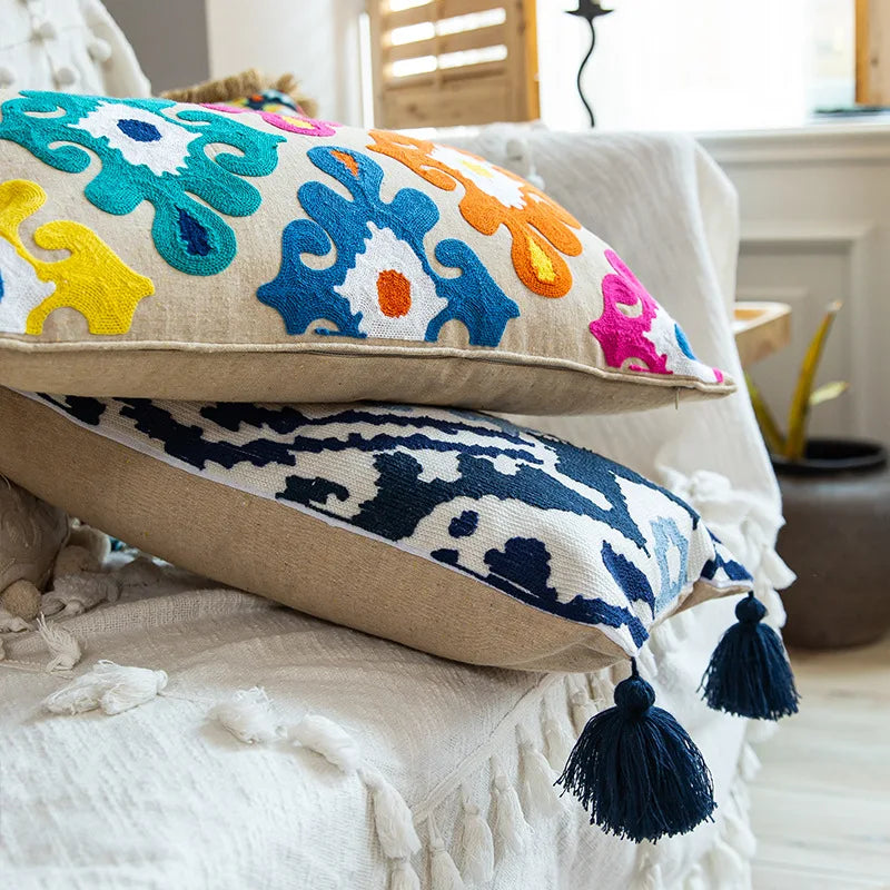 Des coussins brodés multicolores sur un lit sont mis en évidence dans cette image, créant une atmosphère chaleureuse et colorée dans la pièce.