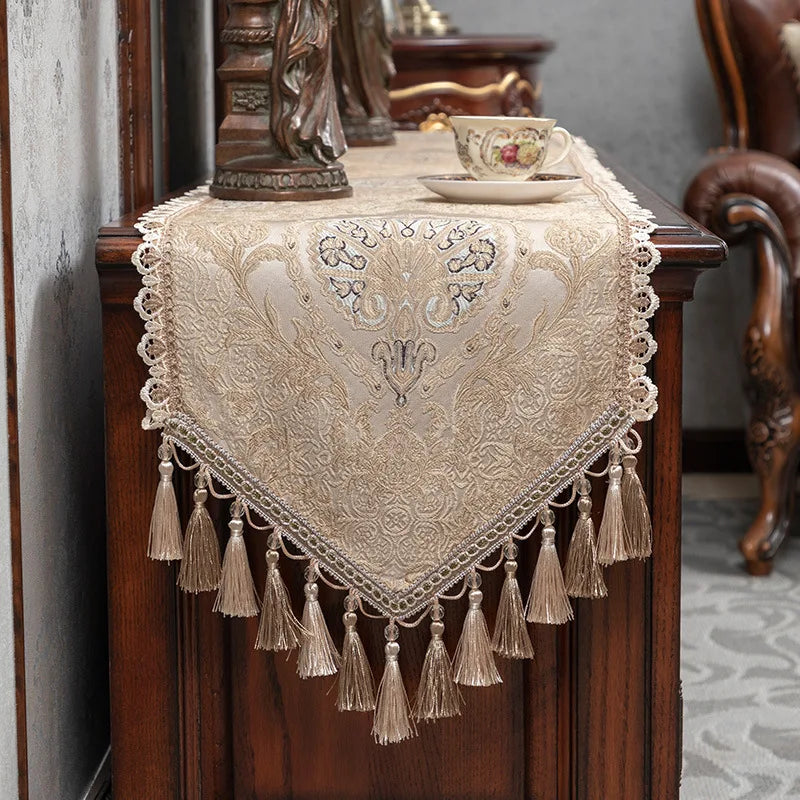 Un chemin de table vintage et orné, aux motifs floraux délicats et aux franges élégantes, crée une atmosphère chaleureuse et raffinée dans cette pièce meublée avec goût.