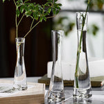 Vase en verre biseauté avec branches fleuries dans une chambre élégante