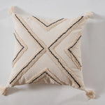 Coussin beige avec motifs noirs géométriques et franges.