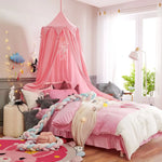 Une chambre de fille décorée avec des tons roses et pastel, avec un lit à baldaquin rose, des oreillers et couvertures moelleux, ainsi que des accessoires décoratifs.