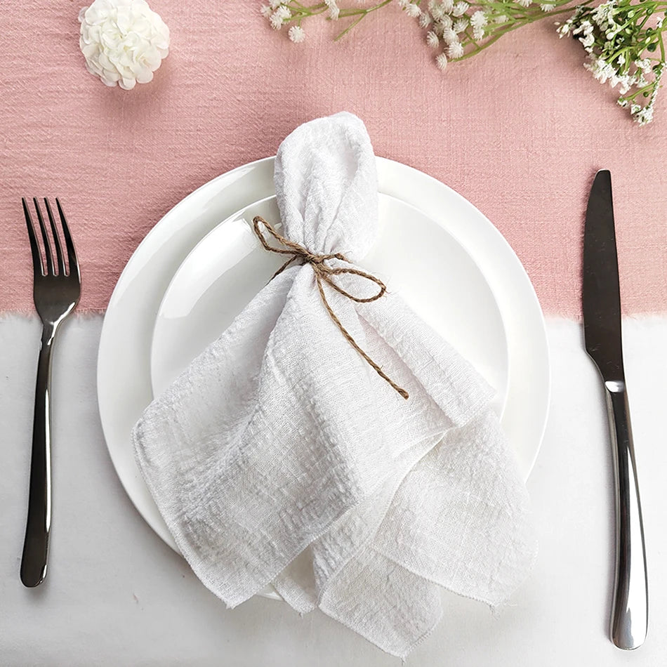 Un service de table élégant avec une serviette blanche attachée avec de la ficelle et des fleurs sur un fond rose pâle.