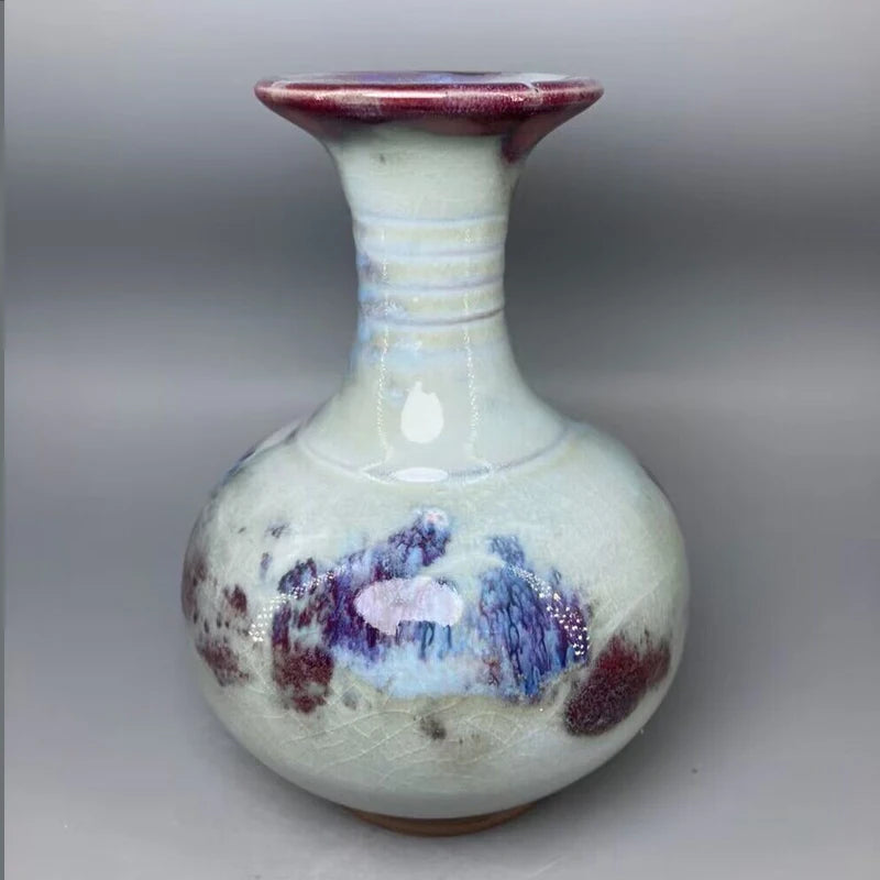 Vase en céramique de style vintage avec des motifs paysagers bleutés et des touches de rouge, créant une composition harmonieuse et élégante.