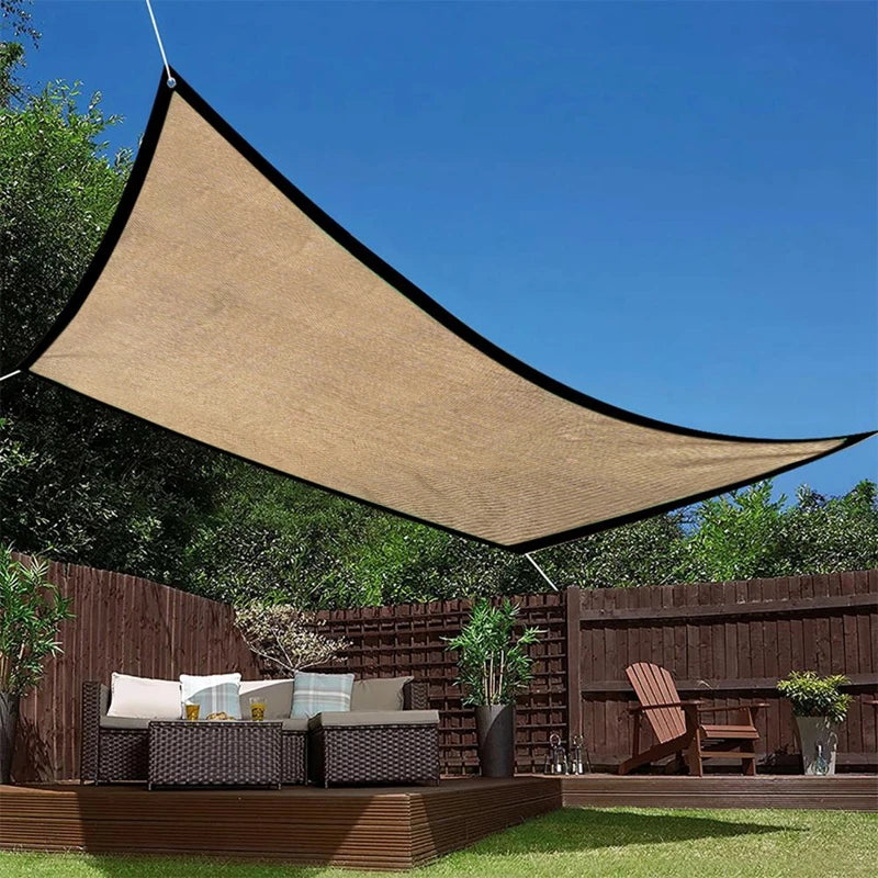 Voile d'ombrage jaune tendue sur terrasse avec mobilier de jardin