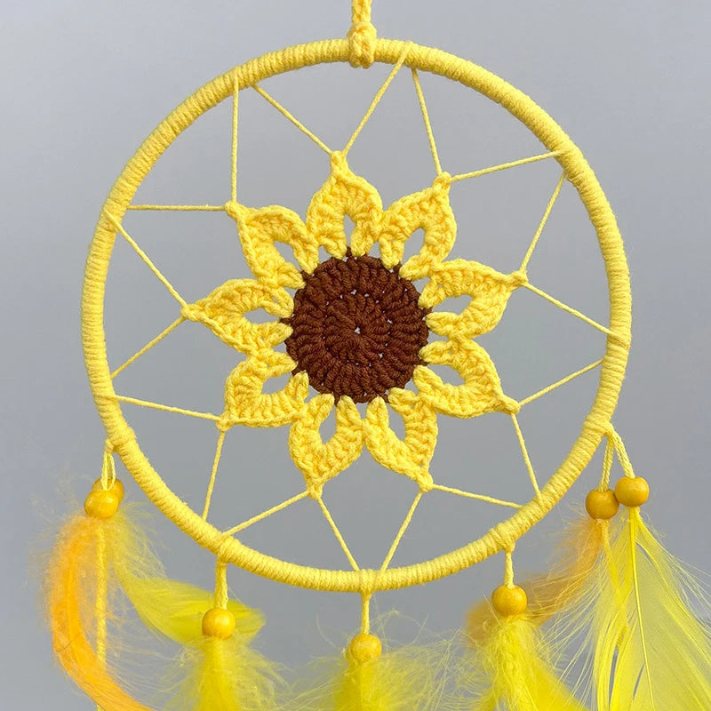 Un magnifique capteur de rêves jaune avec une belle fleur crochetée au centre, entouré de plumes jaunes.