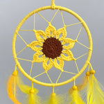 Un magnifique capteur de rêves jaune avec une belle fleur crochetée au centre, entouré de plumes jaunes.