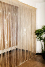 Rideau à fils beige suspendu, idéal pour créer une séparation élégante dans votre intérieur. Complément parfait pour ajouter une touche de sophistication à votre décoration. Ajoute du charme et de la légèreté à la pièce tout en offrant une séparation subtile. Convient à différents types d'espaces tels que salons, chambres, ou bureaux.