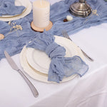 La table est joliment dressée avec des assiettes blanches, des couverts argentés et des accents bleu clair, créant une ambiance élégante et apaisante.