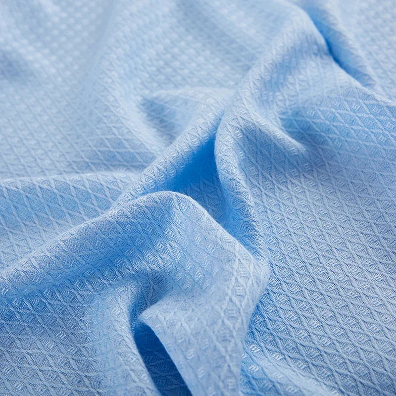 Texture en fil bleu pâle formant des motifs géométriques sur un tissu froissé.