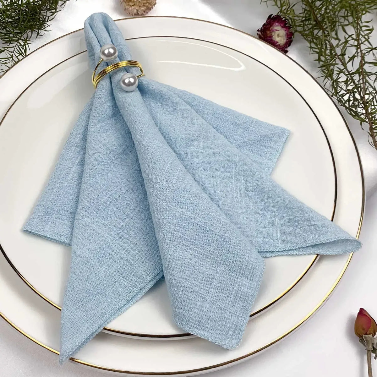 Un arrangement de table élégant avec une serviette bleue en textile entourée d'éléments décoratifs naturels.