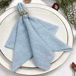 Un arrangement de table élégant avec une serviette bleue en textile entourée d'éléments décoratifs naturels.