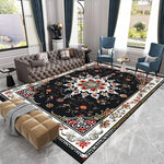 Un élégant salon avec un grand canapé capitonné gris, des fauteuils bleus, une table basse et un magnifique tapis persan noir orné de motifs floraux colorés.
