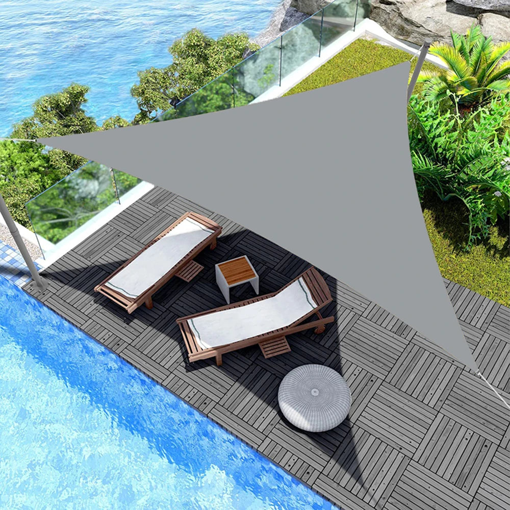 Voile d'ombrage triangulaire grise sur un patio avec meubles