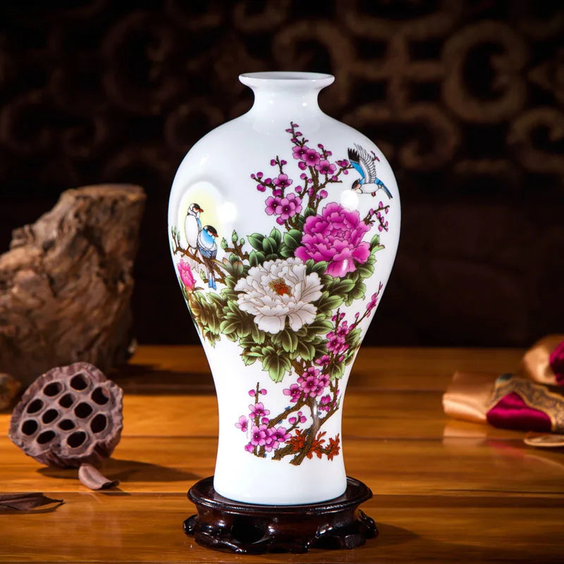 Vase en porcelaine blanc avec un motif floral coloré et des oiseaux, posé sur une table en bois.