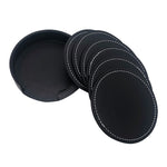 Coasters en cuir noir avec coutures apparentes, rangés dans un boîtier rond.